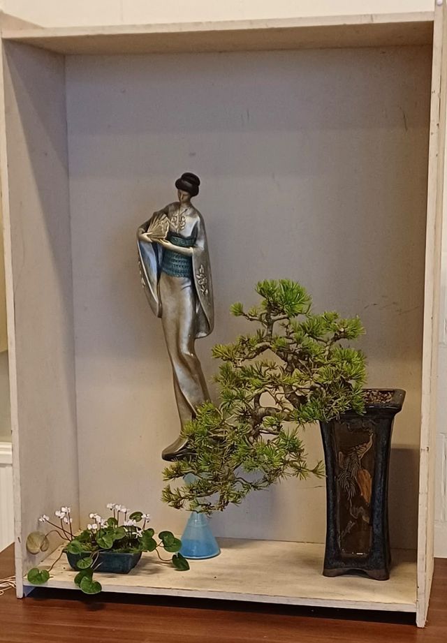 Tokonoma met een den in een hoge pot, een beeld en een cyclaam als accentplant.
