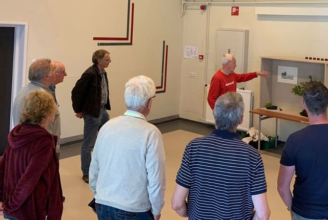 Een lid geeft uitleg bij een tokonoma-opstelling aan een groep leden.