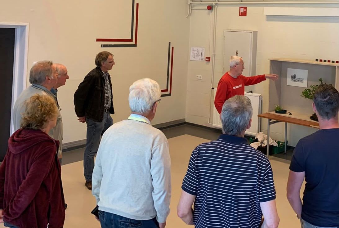 Een lid geeft uitleg bij een tokonoma-opstelling terwijl een groep leden toekijkt.